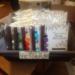 Woven basket display filled with individually packaged Inspirational Book Bracelets featuring colorful beaded designs and a "MADE IN VICTORIA, BC" sign attached to the front.
