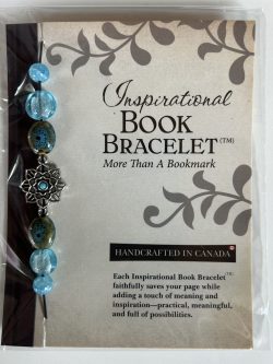 Packaged Inspirational Book Bracelet featuring light sky-blue disc beads, speckled brown-teal ceramic accents, and an intricate silver lotus flower spacer with a turquoise center mounted on a branded backing card.