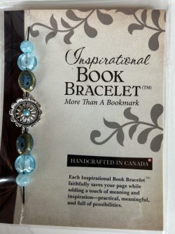 Packaged Inspirational Book Bracelet featuring light sky-blue disc beads, speckled brown-teal ceramic accents, and a circular silver sunflower spacer with a turquoise center mounted on a branded backing card.